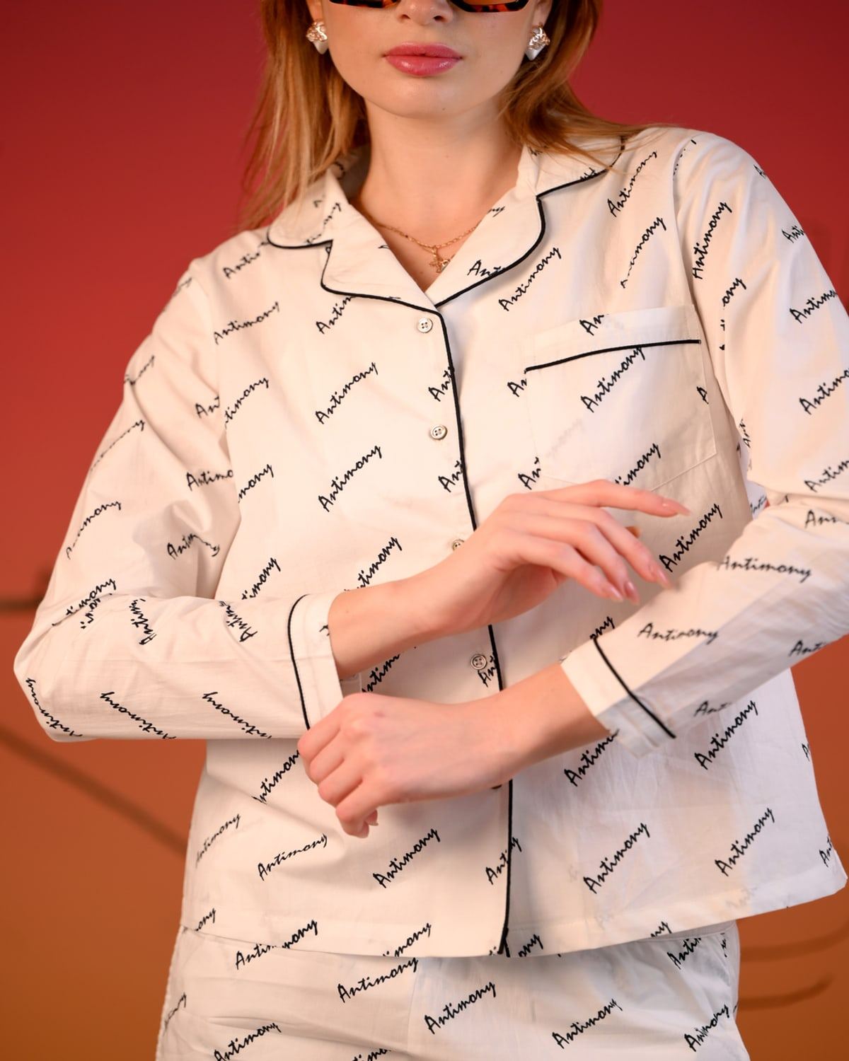 Ivory pajama-style co-ord with ANTIMONY script and black piping, buttoned shirt and matching trousers.